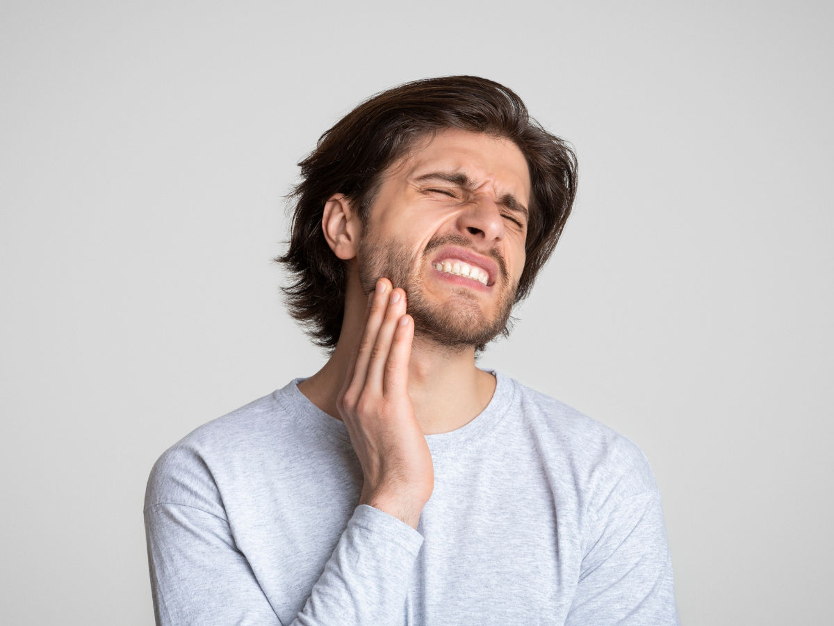 man holding his jaw suffering from tmj pain